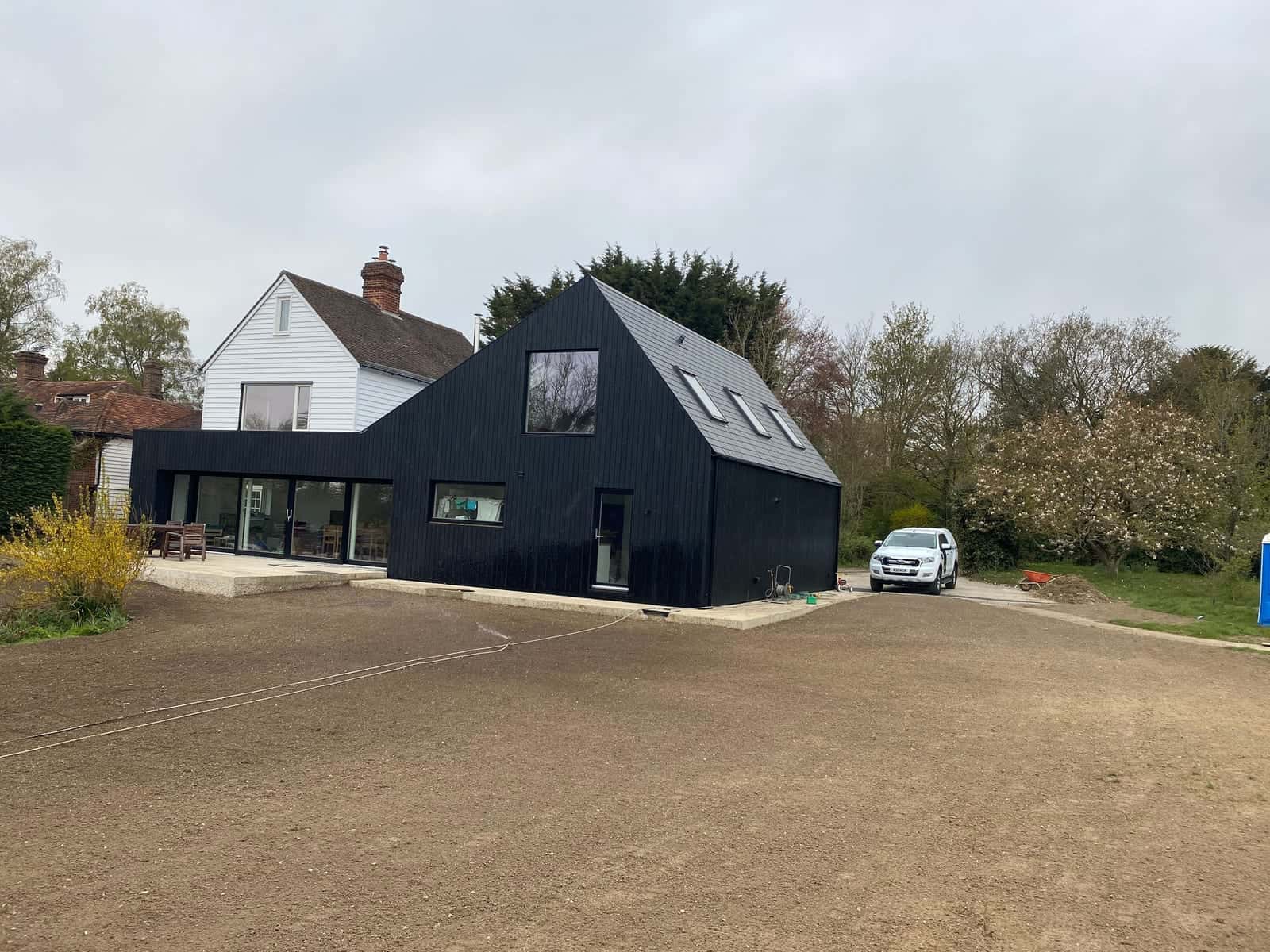 Ground levelled and raked for a lawn in front of a new black timber-clad house