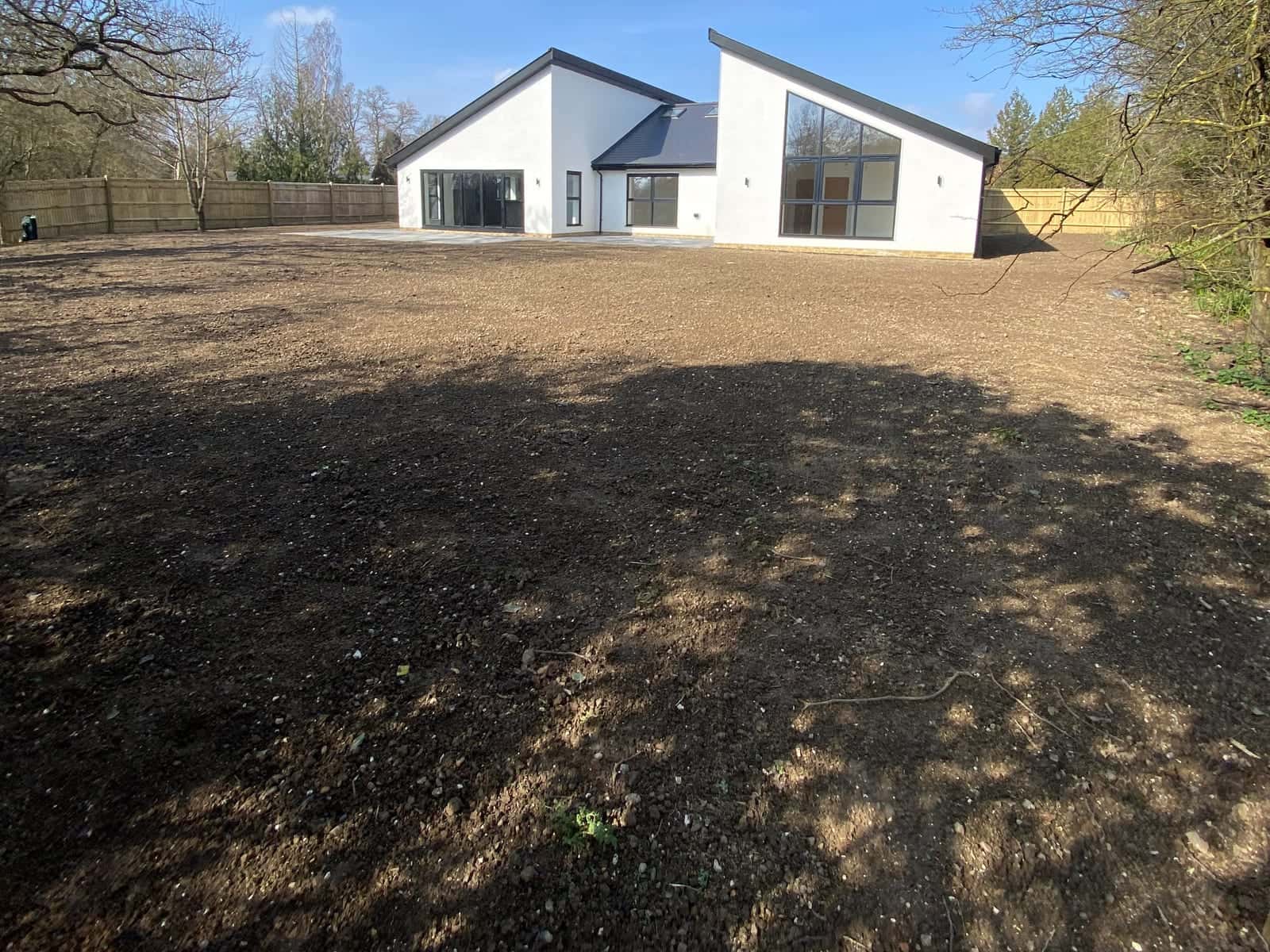 Bare ground graded and levelled in front of a new-build house, ready for a lawn
